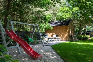 a playground with a slide and a bench and a shed at MEDUSA apartamenty i bungalowy in Niechorze