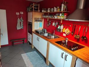a kitchen with red walls and white cabinets and a sink at Ostello del Parco di Cicogna in Cicogna