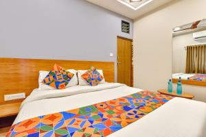 a bedroom with a large bed with a colorful comforter at FabExpress Gokul Villa in Ahmedabad