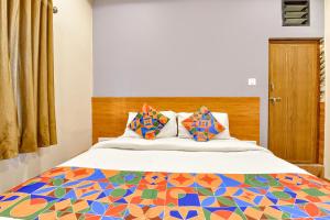 FabExpress Gokul Villa في أحمد آباد: غرفة نوم مع سرير مع لحاف ملون