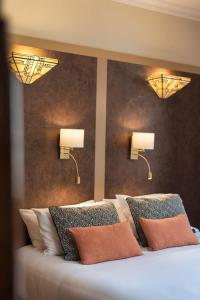 a bedroom with two lights on the wall and a bed at Garlande Hôtel Avignon Centre in Avignon