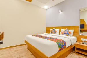 FabExpress Gokul Villa في أحمد آباد: غرفة نوم بسرير كبير مع شراشف بيضاء