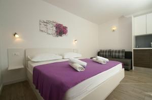 ein Schlafzimmer mit einem lila Bett mit zwei Kissen darauf in der Unterkunft Apartmani Villa Dijana-Promajna in Promajna