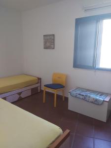 a room with two beds and a chair and a window at La portuense in Castro di Lecce