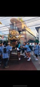 un grupo de chicas con uniformes azules y blancos parados alrededor de una máquina en 桜宿-ダブルベッドの小さなガーデンルーム, en Tokio