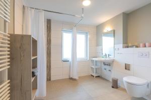 ein Bad mit einem WC, einem Waschbecken und einem Fenster in der Unterkunft Waastwinj - 500m vom Strand in Utersum