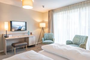 Pokój hotelowy z łóżkiem, 2 krzesłami i biurkiem w obiekcie Waastwinj - 500m vom Strand w mieście Utersum