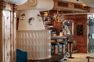 a bar with stools and a counter in a room at Hotel Belvedere in San Martino di Castrozza