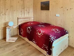a bedroom with a bed with a red comforter at Ferienhaus LebenPUR Bio-Ferienhaus aus Holz in Parin
