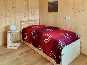 une chambre avec un lit avec une couette rouge dans l'établissement Ferienhaus LebenPUR Bio-Ferienhaus aus Holz, à Parin 14 autres photos