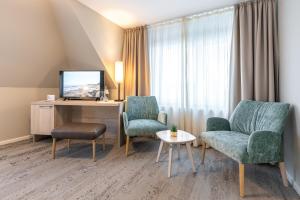 ein Hotelzimmer mit 2 Stühlen, einem Schreibtisch und einem TV in der Unterkunft Waastwinj - 500m vom Strand in Utersum