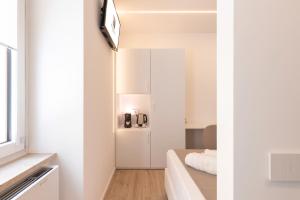 a small white room with a bed and a mirror at Metropolitan Rooms in Cagliari