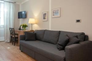 トレントにあるLa Canonica Suite Apartments New Locationのリビングルーム(グレーのソファ、デスク付)