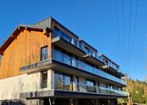 un edificio de madera con balcones de cristal. en Kryształ Górski apartament z sauną, en Szczyrk