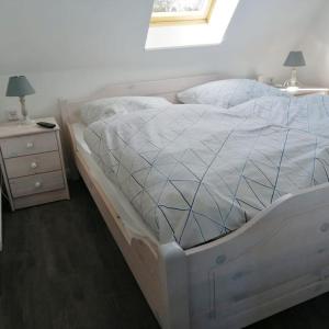 a bed with a white comforter and a night stand at Ferienwohnung Leuchtturmkieker in Schlagsdorf auf Fehmarn in Fehmarn