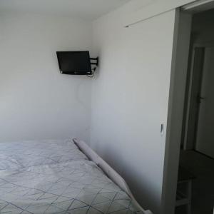 Habitación blanca con cama y TV en la pared en Ferienwohnung Leuchtturmkieker in Schlagsdorf auf Fehmarn, en Fehmarn