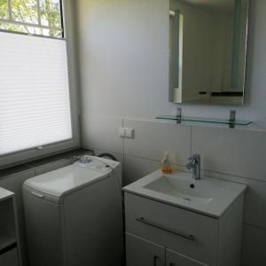 a white bathroom with a sink and a mirror at Ferienwohnung Leuchtturmkieker in Schlagsdorf auf Fehmarn in Fehmarn