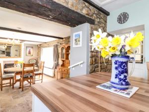 un vase de fleurs jaunes sur une table dans une cuisine dans l'établissement West Farm Cottage, à Morpeth