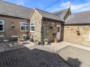 une maison en pierre avec un patio, une table et des chaises dans l'établissement West Farm Cottage, à Morpeth