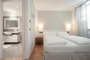 Biała sypialnia z 2 łóżkami i łazienką w obiekcie La Canonica Suite Apartments New Location w Trydencie