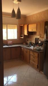 kuchnia z drewnianymi szafkami i lodówką w obiekcie Villa à la compagne w mieście Al-Muhammadijja