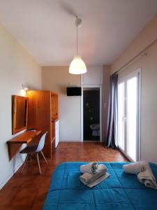 a bedroom with a blue bed and a desk at Perdika Mare Guesthouse in Perdika