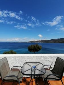 een tafel en stoelen op een patio met uitzicht op het water bij Perdika Mare Guesthouse in Perdhika