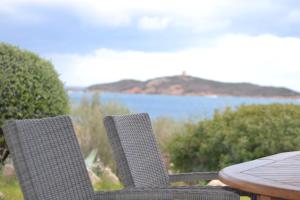 duas cadeiras e uma mesa com vista para a água em Les Hauts de Pinarello em Sainte-Lucie de Porto-Vecchio