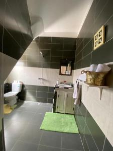 uma casa de banho com lavatório, WC e azulejos verdes em Maison Mina em Oualidia