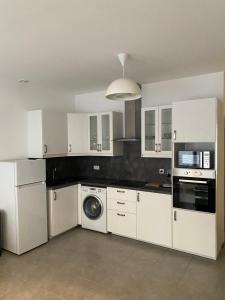 cocina con armarios blancos y lavadora en Appartement Les Halles Narbonne, en Narbona