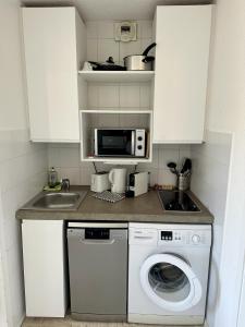 eine Küche mit einer Waschmaschine und einer Mikrowelle in der Unterkunft vue marina et vue montagne in Mandelieu-la-Napoule