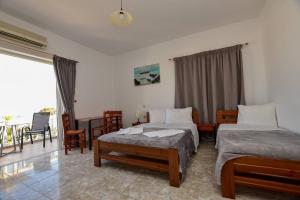 a bedroom with two beds and a table and chairs at KOYNTOYRA ROOMS in Kountoura Selino