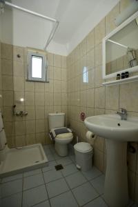 een badkamer met een wastafel, een toilet en een spiegel bij KOYNTOYRA ROOMS in Kountoura Selino