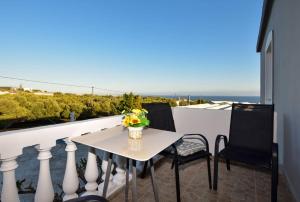 een tafel en stoelen op een balkon met uitzicht op de oceaan bij KOYNTOYRA ROOMS in Kountoura Selino
