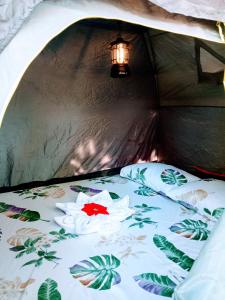 een bed in een tent met een rode bloem erop bij Akoya Beach Sunset Camp in El Nido +33 foto's