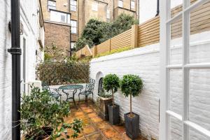 a small courtyard with a table and chairs on a balcony at Fabulous Chelsea 2 bed in London