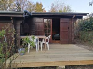 a wooden deck with a table and chairs in a cabin at Chalet en pleine nature au bord d'un étang in Lanvallay