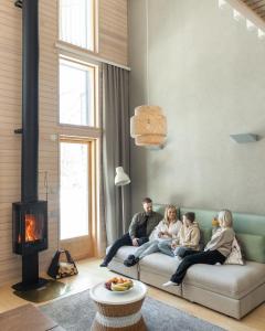 a family sitting on a couch in a living room with a fireplace at Nova Skyland Hotel in Rovaniemi