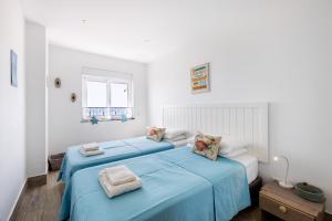 2 camas en una habitación blanca con sábanas azules en Beira Mar Apartment, en Armação de Pêra