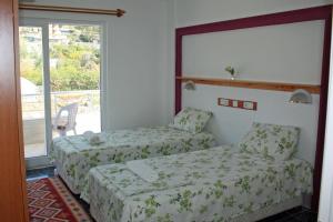 two beds in a hotel room with a window at Rose Hotel B&B in Patara