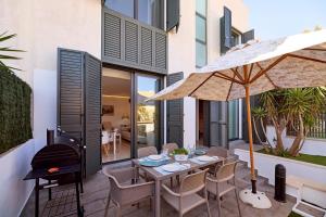 a patio with a table with an umbrella and a grill at Apartamento tríplex nuevo en la Savina in La Savina