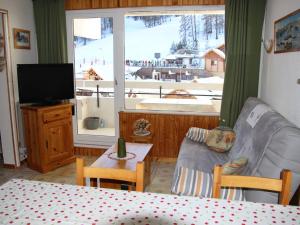 ein Wohnzimmer mit einem Sofa, einem TV und einem Fenster in der Unterkunft Appartement Puy-Saint-Vincent, 2 pièces, 6 personnes - FR-1-330G-53 in Puy-Saint-Vincent