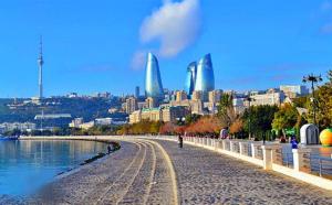 a person walking on a beach with a city in the background at Essam Deluxe Hotel in Baku