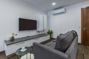 a living room with a couch and a flat screen tv at Sandstone A8 Marsascala - 15minute drive to Valletta in Marsaskala