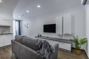 a living room with a couch and a flat screen tv at Sandstone A8 Marsascala - 15minute drive to Valletta in Marsaskala