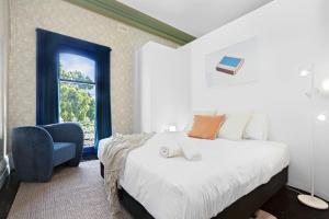 een slaapkamer met een bed, een stoel en een raam bij The White House Fitzroy - One of the largest single dwelling accommodations in Melbourne