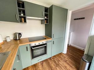 a kitchen with green cabinets and a stove at Hydeaway beautiful 3 bedroom house in a great location in Bournemouth