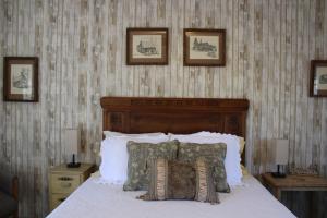 Schlafzimmer mit einem Bett mit Kissen und Bildern an der Wand in der Unterkunft The Bonnie Inn Unit 1 in San Andreas