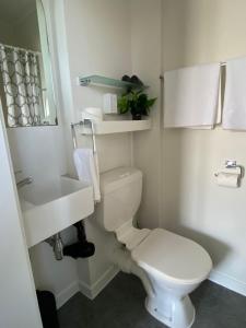 a white bathroom with a toilet and a sink at Bavaria Boutique Hotel in Auckland