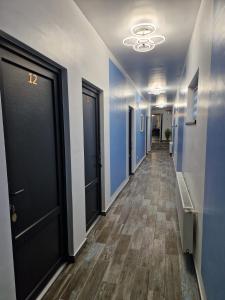 - un couloir avec des portes noires, des murs bleus et du parquet dans l'établissement Pensiunea Magia Voroneţului, à Voroneț